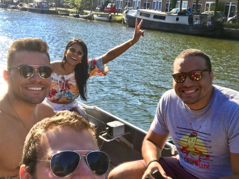 Trois femmes et un homme en vêtements blancs sur un bateau, employé Boats4rent sur le quai