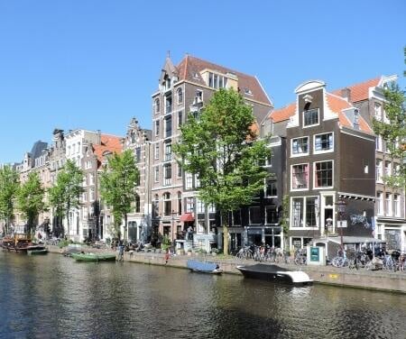 Maisons de maîtres le long des canaux d'Amsterdam avec des bateaux amarrés par une belle journée.
