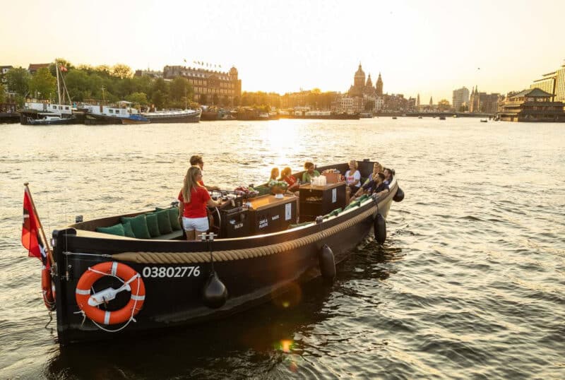 Bateau ouvert avec skipper au coucher du soleil sur les canaux d'Amsterdam