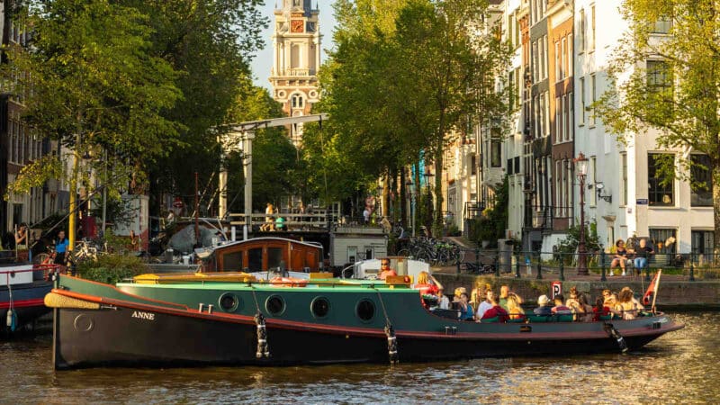Bateau classique au coucher du soleil sur les canaux d'Amsterdam avec un groupe